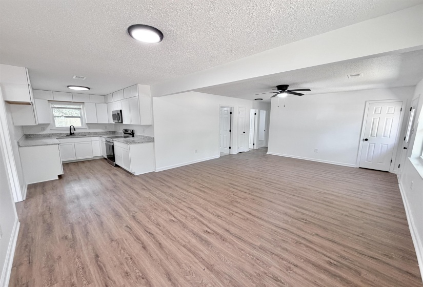 Open-concept living area featuring wood-finish flooring, recessed lighting, and a ceiling fan