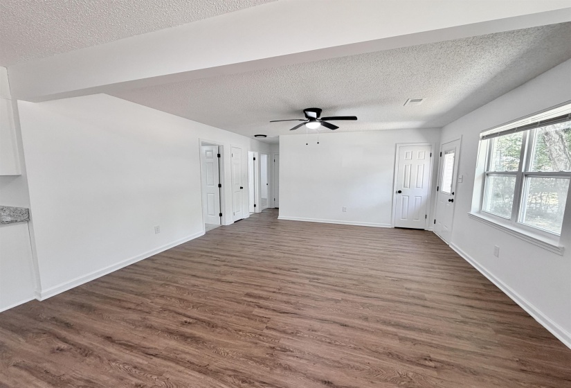 Open-concept living area featuring wood-finish flooring, white baseboards, and a contemporary ceiling fan