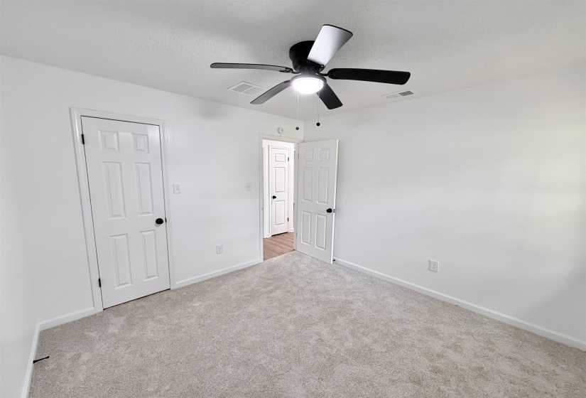 Carpeted room featuring a ceiling fan with light, white walls, and white trim