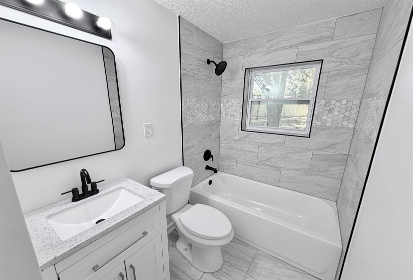 Bathroom featuring a white vanity with integrated sink, black fixtures, and a framed mirror