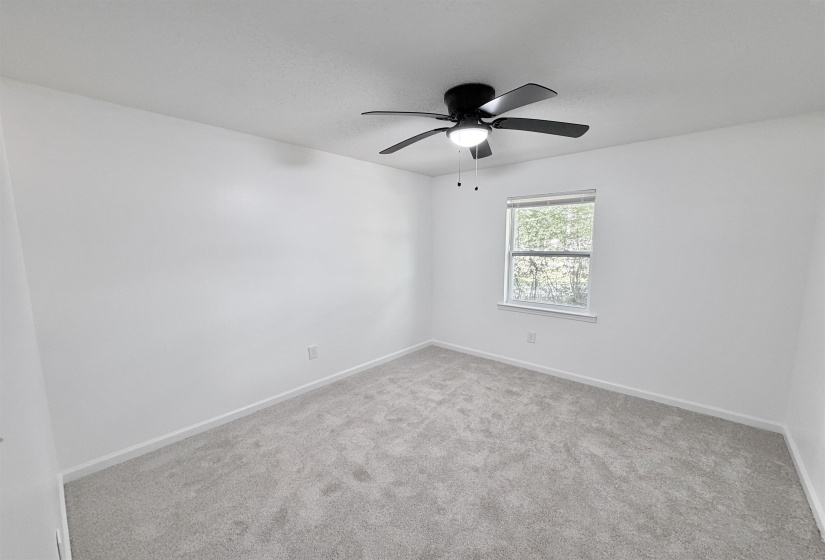 Room featuring light gray carpet, white walls, a single window with blinds, and a black ceiling fan with an integrated light fixture