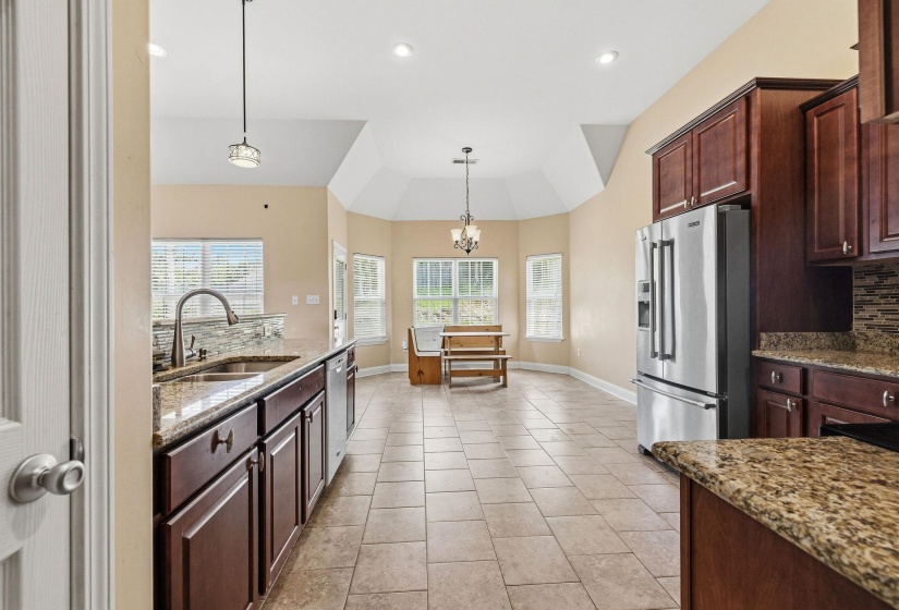 Kitchen featuring stainless steel appliances, dark wood cabinetry, and granite countertops