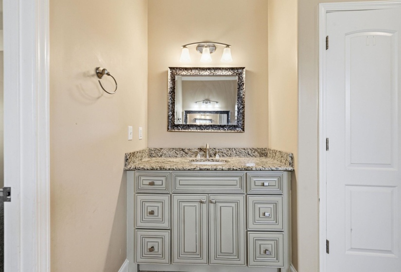 Bathroom vanity featuring a granite countertop, integrated sink, and brushed nickel faucet