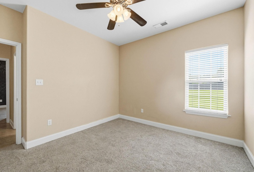 Carpeted interior room featuring a vaulted ceiling with a ceiling fan, a single window with blinds, and light-colored walls