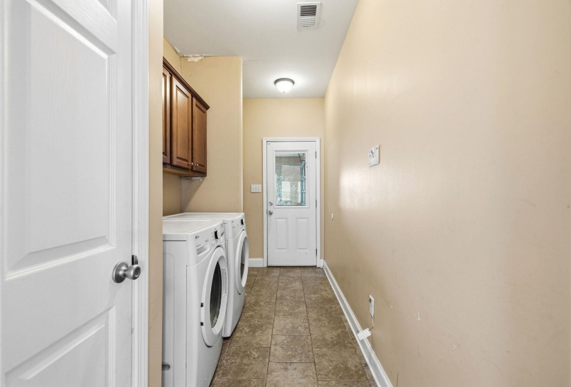 Laundry area featuring tile flooring and overhead cabinetry for storage