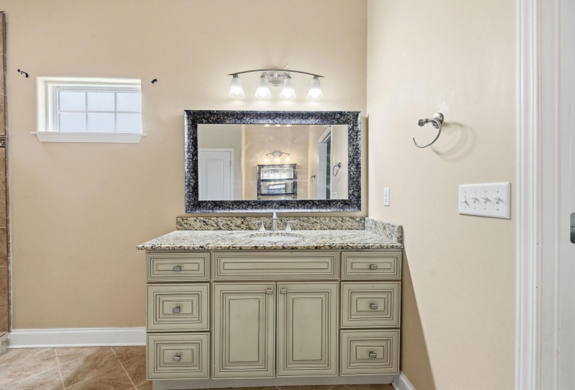 Bathroom vanity featuring a light-toned cabinetry, a granite countertop, and a single undermount sink