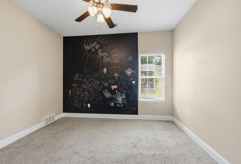 Room featuring a chalkboard accent wall, neutral carpeting, and a window with blinds