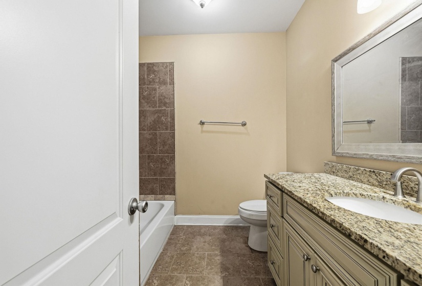 Bathroom featuring a single vanity with a granite-style countertop, undermount sink, and brushed nickel faucet