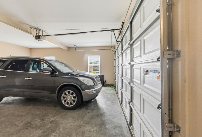 Attached two-car garage featuring a paneled overhead door, concrete flooring, painted walls, and an automatic door opener system