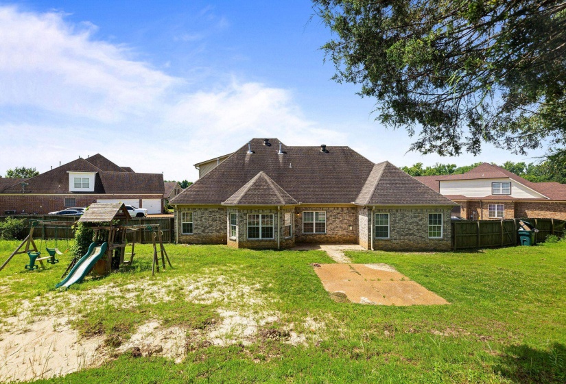 Rear exterior featuring brick facade, multiple windows, and a paved patio area