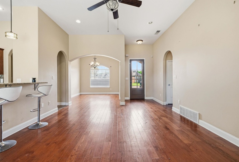 Open-concept living area featuring wood-finish flooring, vaulted ceilings, recessed lighting, and arched doorways