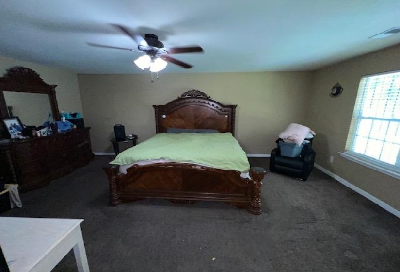 Spacious room featuring neutral wall tones, window with horizontal blinds, and a ceiling fan with integrated lighting
