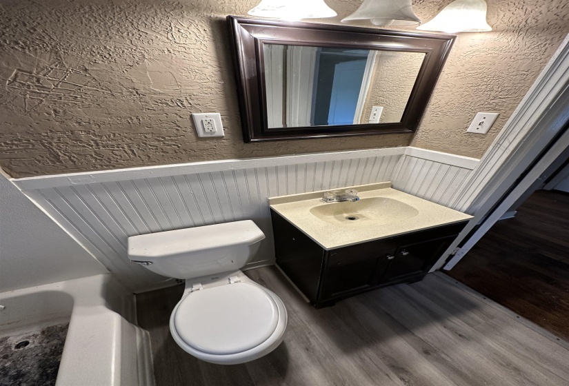Bathroom featuring wood-finish flooring, white beadboard paneling, and a vanity with a light-colored countertop
