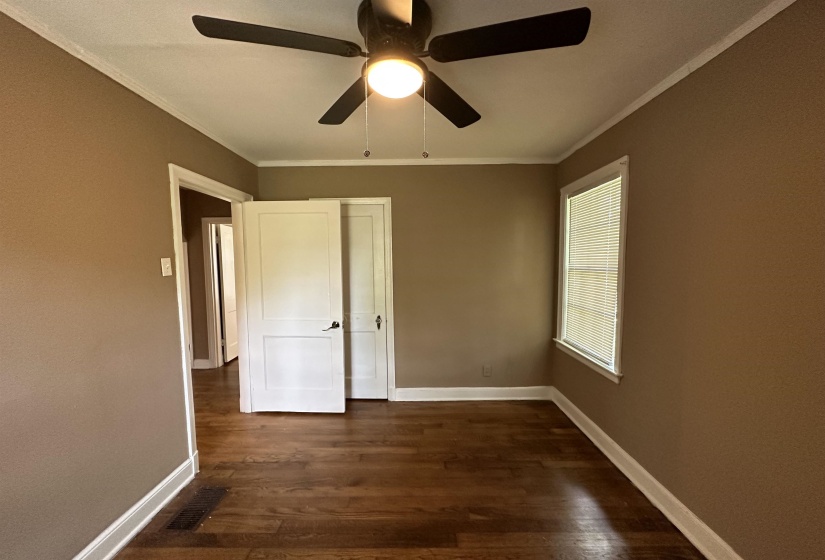 Interior room featuring wood-finish flooring, a ceiling fan with integrated lighting, and a window with horizontal blinds