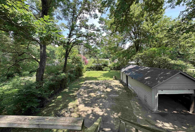 Expansive concrete driveway extending to a detached garage structure with a single garage door opening