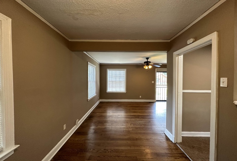 Open-concept living space featuring wood-finish flooring throughout, light tan walls, and white trim