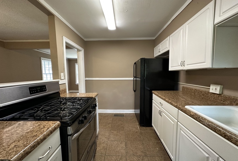 Kitchen featuring white cabinetry, speckled countertops, and tile flooring