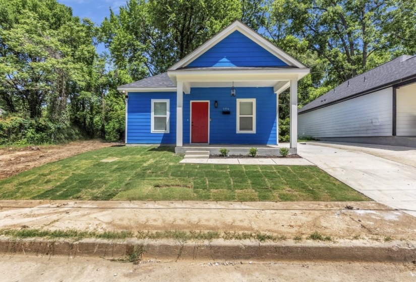 Vibrant blue exterior featuring a contrasting red entry door, covered front porch, and newly installed sod