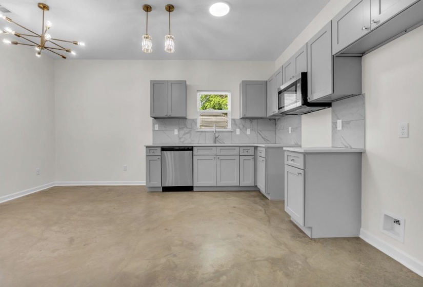 Modern kitchen featuring light gray cabinetry, stainless steel appliances, and a white patterned backsplash