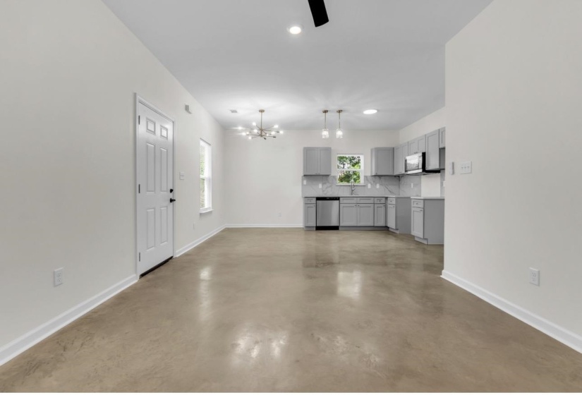 Open-concept living space featuring concrete flooring, a modern kitchen with gray cabinetry, stainless steel appliances, and a tiled backsplash