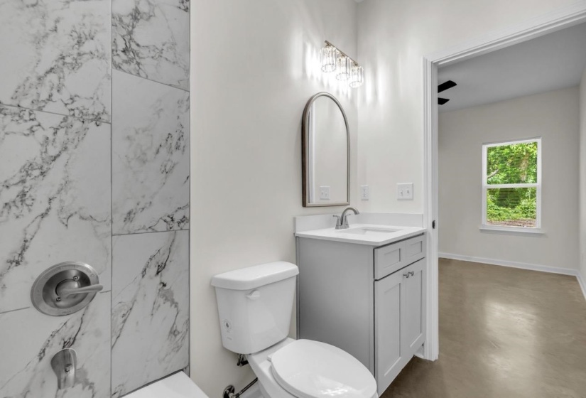 Bathroom featuring a white vanity with a rectangular basin sink, brushed nickel faucet, and a wall-mounted arched mirror
