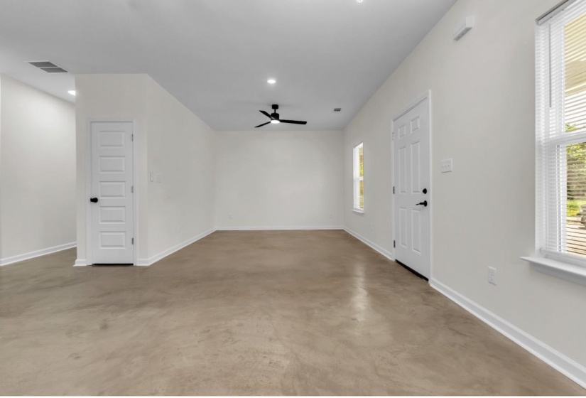 Spacious interior featuring a neutral color palette, ceiling fan, recessed lighting, and durable concrete-finish flooring