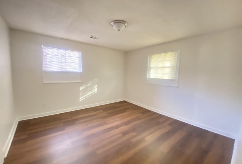 Spare room featuring healthy amount of natural light and dark wood-style flooring