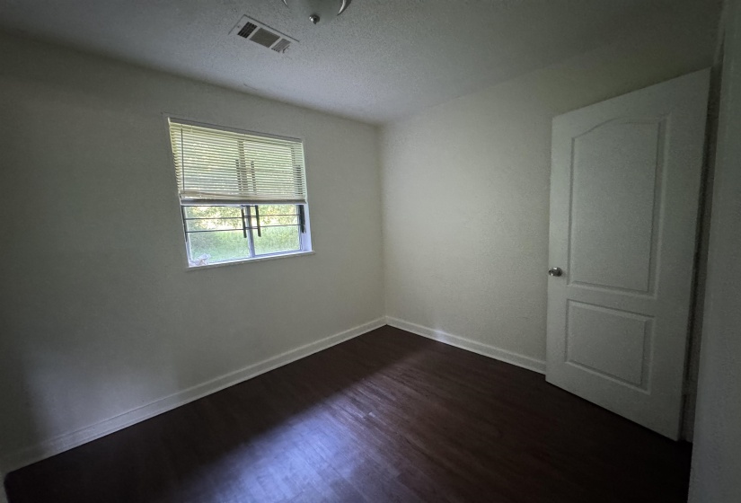 Room featuring wood-finish flooring, white baseboards, and light-colored walls