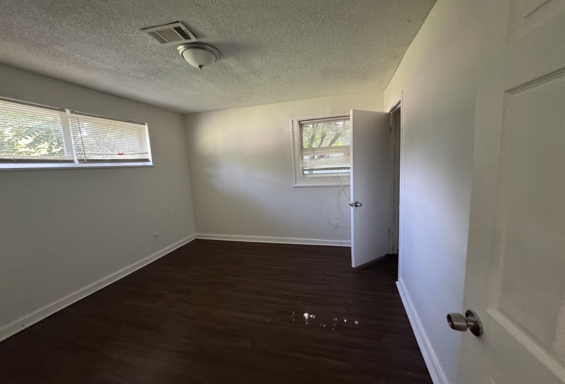 Room featuring dark wood-finish flooring, white baseboards, and light-colored walls