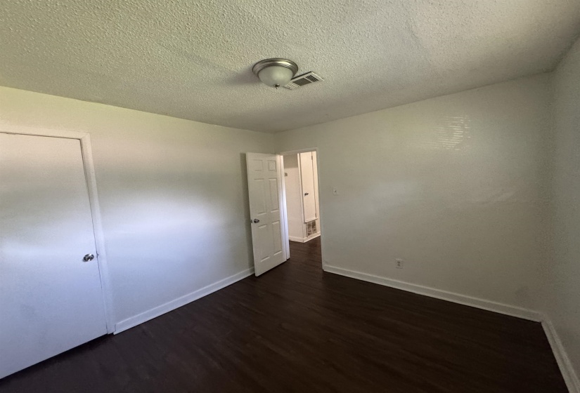 Interior room featuring dark wood-finish flooring, white walls, and a ceiling-mounted light fixture