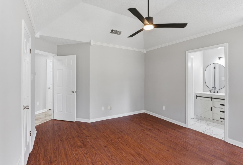 Spacious room featuring vaulted ceilings, wood-finish flooring, and a modern ceiling fan