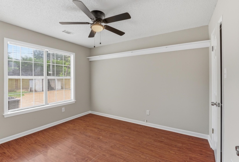 Room featuring wood-finish flooring, a contemporary ceiling fan, and a large window with blinds