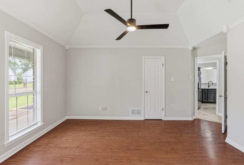 Spacious room featuring wood-finish flooring, vaulted ceiling, and a modern ceiling fan