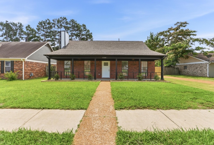 Brick facade home with a covered front porch featuring black columns and railing