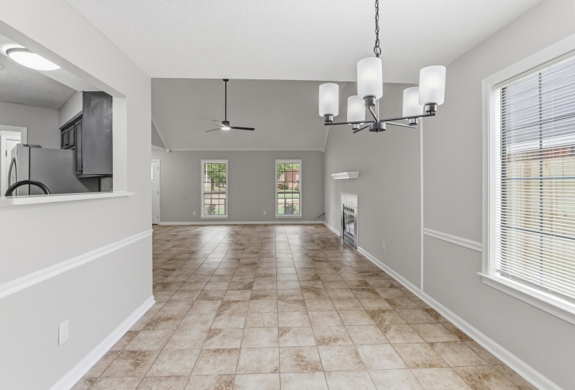 Dining area with a contemporary chandelier, tile flooring, and a pass-through opening to the kitchen