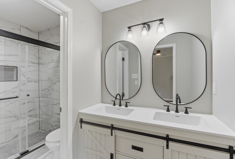 Vanity featuring dual rectangular sinks, matte black fixtures, and two oval mirrors