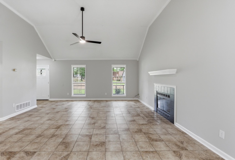 Spacious living area featuring vaulted ceilings, tile flooring, and a ceiling fan