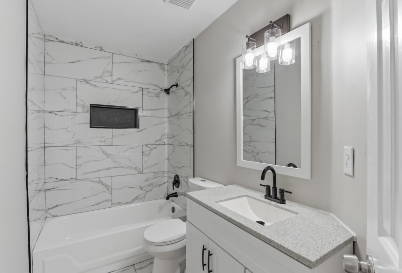 Bathroom featuring a white vanity with a light speckled countertop, undermount sink, and matte black faucet