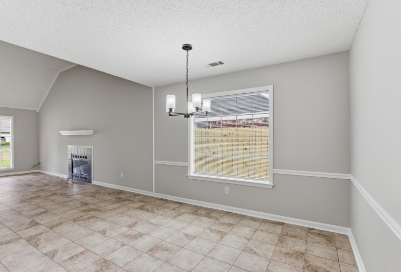 Spacious room featuring tile flooring, a contemporary chandelier, and a large window with blinds