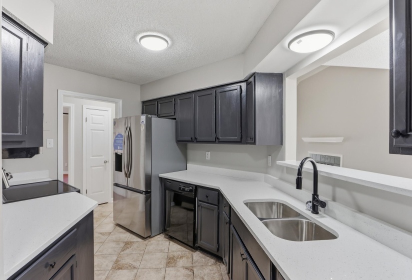 Kitchen featuring dark cabinetry, light countertops, dual basin sink with gooseneck faucet, and tile flooring