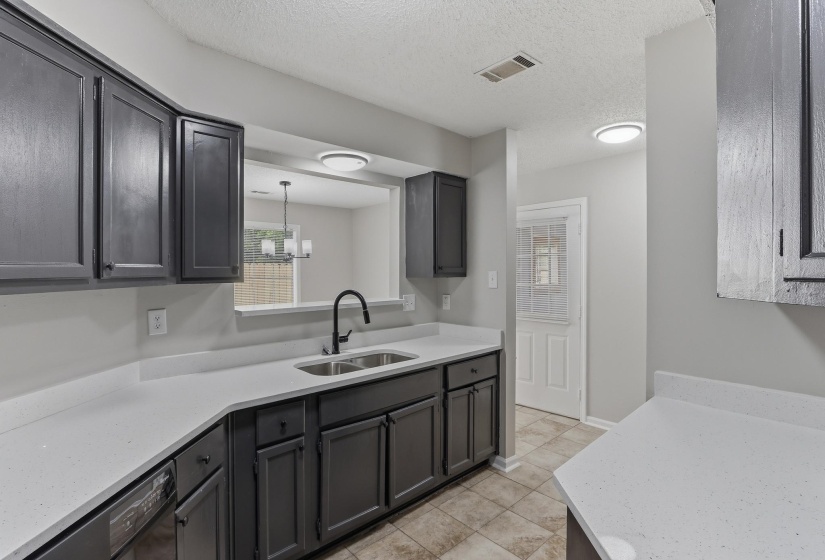 Kitchen featuring dark cabinetry, light countertops, a double-basin stainless steel sink with a gooseneck faucet, and tile flooring