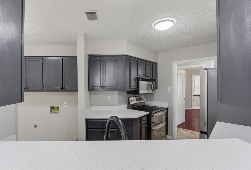 Kitchen featuring dark-finished cabinetry, stainless steel appliances, and white countertops