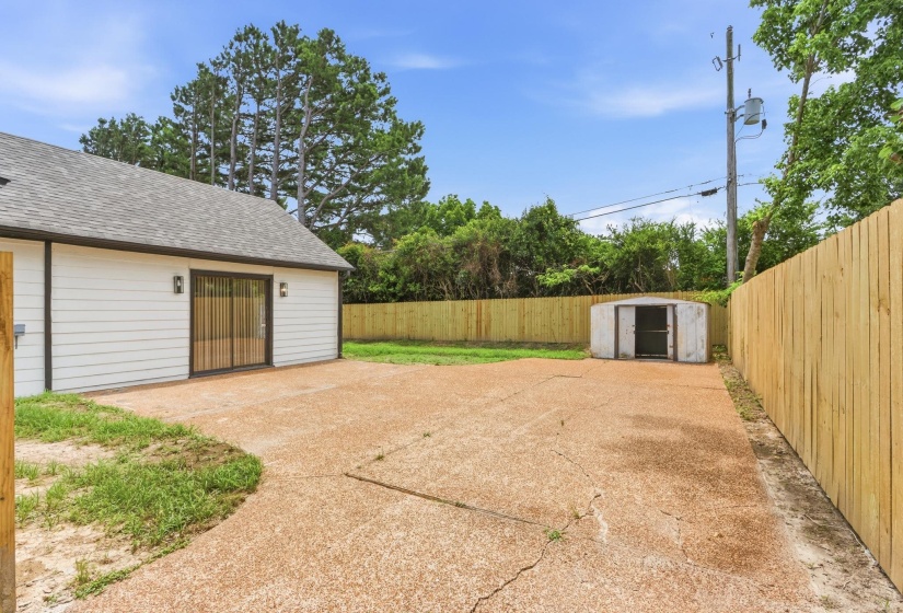 Private backyard featuring a concrete patio, wood privacy fencing, and a storage shed