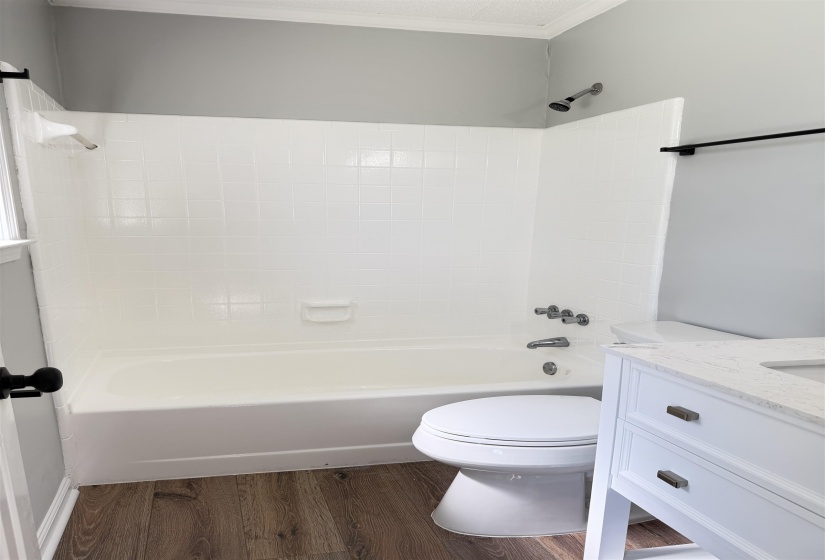 Bathroom featuring a full white bathtub with subway tile surround and coordinating shower fixture