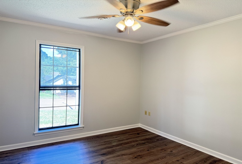 Windowed room featuring dark wood-finish flooring, light-toned walls, white trim, and a ceiling fan with integrated lighting