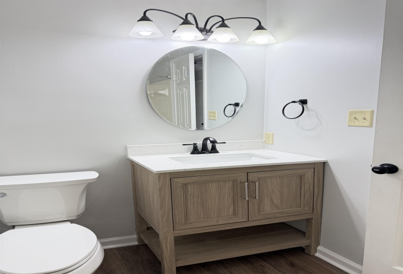 Bathroom featuring a wood-finish vanity with a white countertop, an undermount sink, and matte black hardware