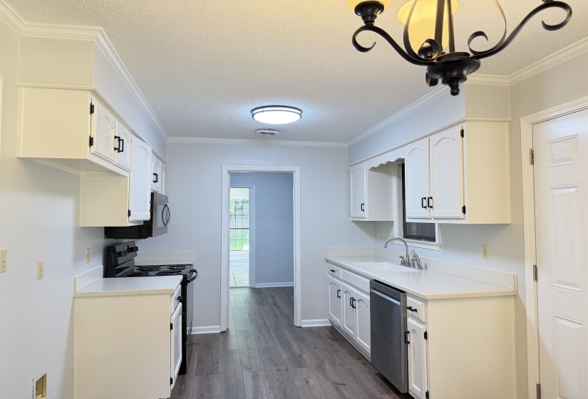 Kitchen featuring white cabinetry, light countertops, wood-finish flooring, and crown molding