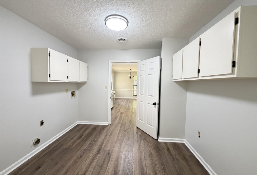 Utility space featuring wood-finish flooring, white wall cabinetry, and light gray walls