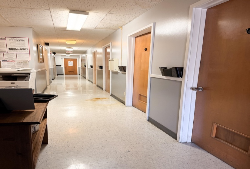 Corridor featuring light flooring and a paneled ceiling