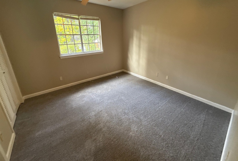 Room featuring a double-hung window, neutral wall paint, white baseboards, and grey carpet flooring